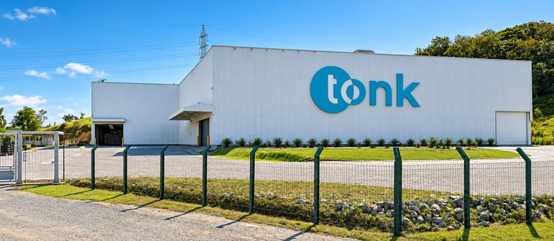 Fachada do galpão da fábrica da Tonk, com o logotipo na parede branca